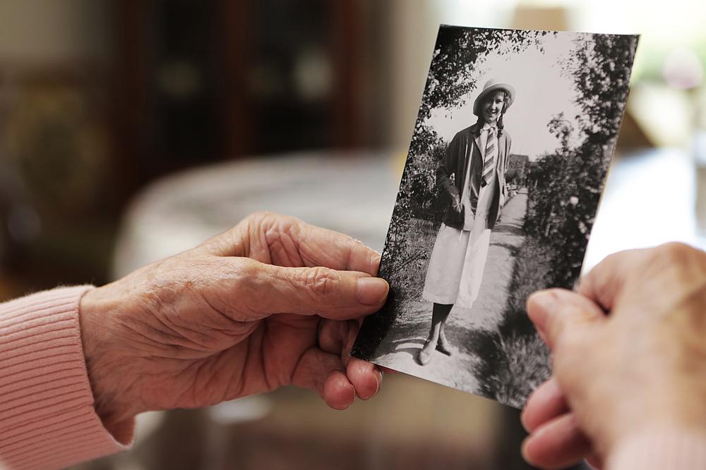 Die Hände einer Seniorin halten ein altes Schwarz-Weiß-Foto.
